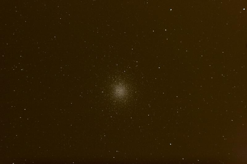 omega-cen-6min.jpg - Omega Centauri seen at an elevation of five degrees through a light dome to the south.  The yellow color comes from sodium vapor street lighting that causes the sky dome.  Still, it's fun to compare the object's apparent size with M5 and M13 seen earlier at the same magnification.